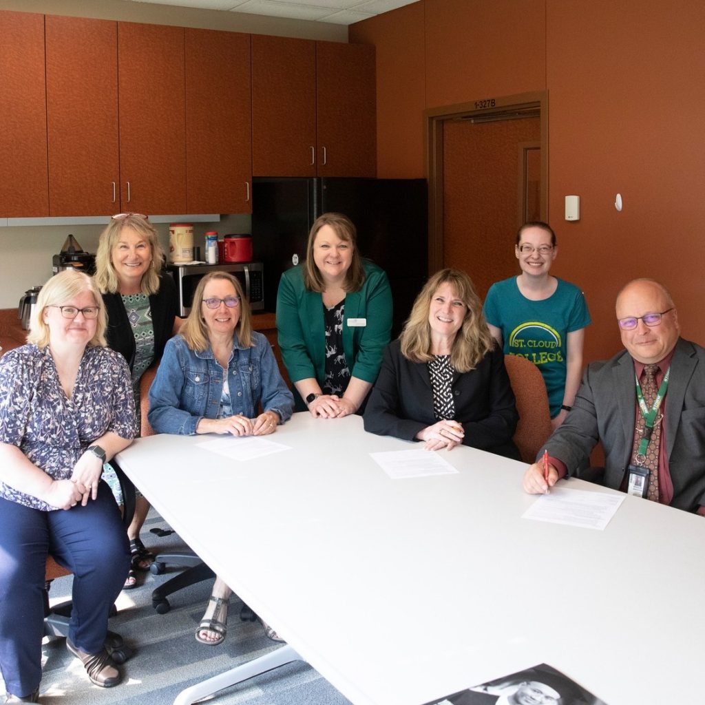 Leadership from BBBS of Central MN, St. Cloud Tech & Community College, and Sauk Rapids-Rice School District sit around a table after signing a partnership agreement.