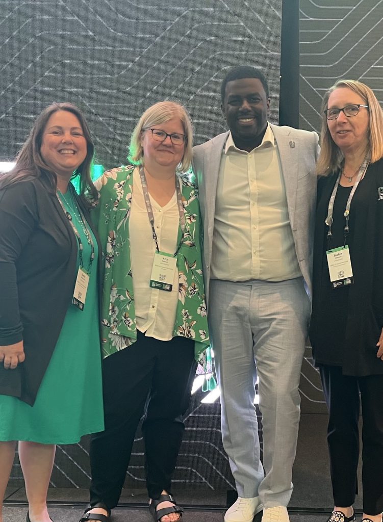 A group of four people pose for a photo to celebrate Ann Matvick winning a national award. From left: Emily Steinmetz, Ann Matvick, Artis Stevens (BBBSA CEO), Jackie Johnson